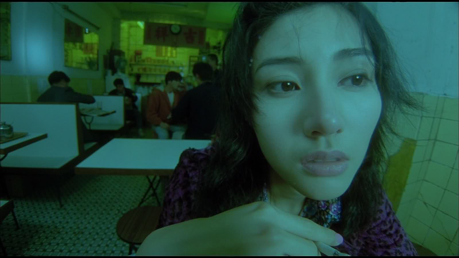 Кадр из фильма Fallen Angels. Главная героиня, партнёр киллера, которую играет Мишель Рейс сидит в кафе и курит сигарету.